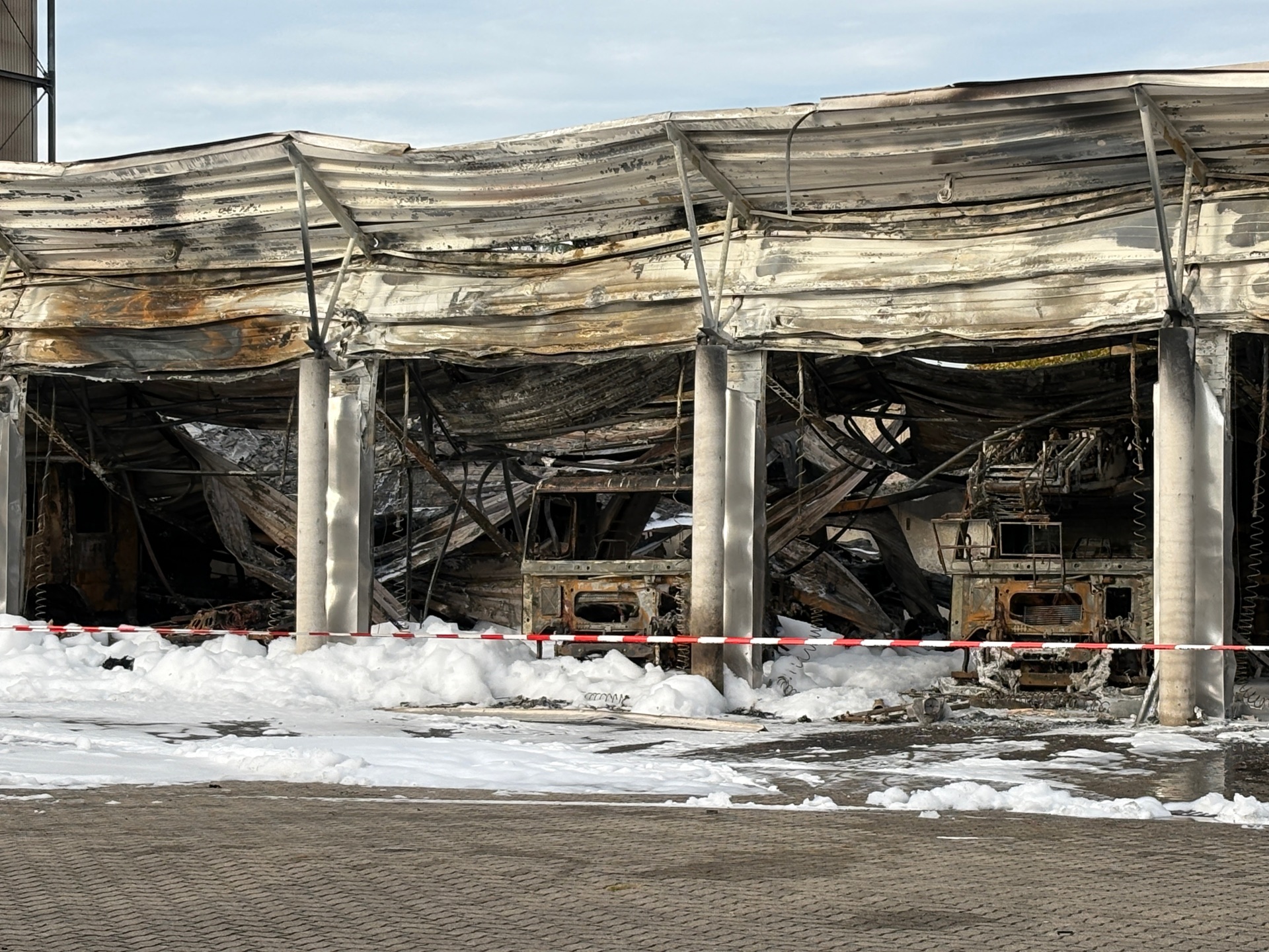In der Fahrzeughalle der Feuerwehr Offenbach an der Queich finden sich heute nur noch Metallgerippe, wo gestern die Fahrzeuge standen. Das Gebäude war komplett mit Löschschaum ausgespritzt worden, um alle Glutnester in der einsturzgefährdeten Halle zu stillen.